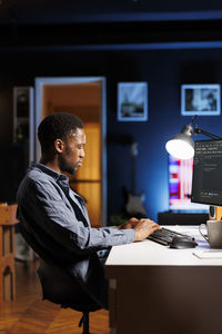 Side view of young man using laptop at office