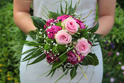 Midsection of woman holding rose bouquet