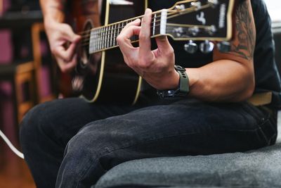 Man playing acoustic guitar songs on the couch