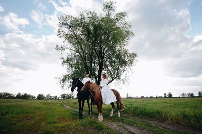 Couple riding horse on field