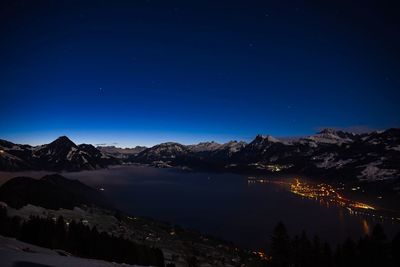 Scenic view of illuminated mountains against clear blue sky at night