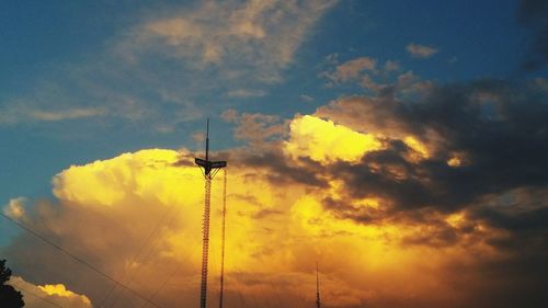 Low angle view of silhouette communications tower against sky during sunset