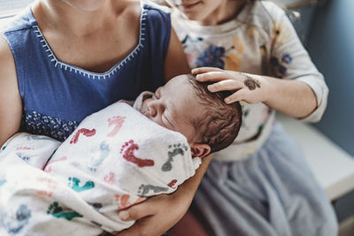 Close up detail of siblings holding newborn brother in hospital