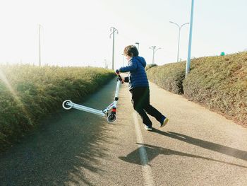 Full length of boy with push scooter on road