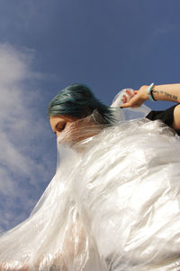 Rear view of woman with arms raised against sky