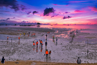 People on beach against sky during sunset