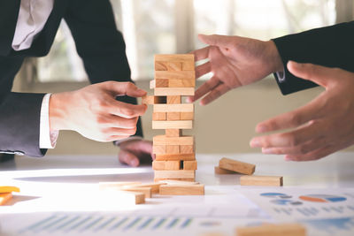 Midsection of businessman with colleague playing jenga