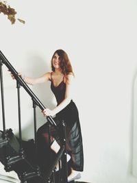 Smiling beautiful woman in dress moving up on steps at home