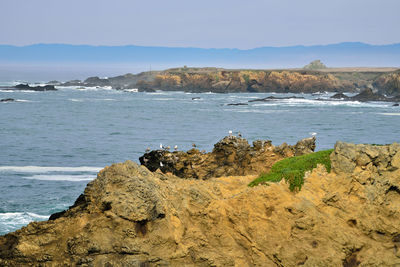 Rock formation on beach against sky