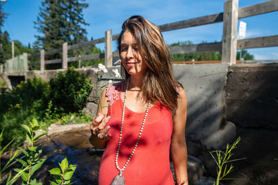 Beautiful young woman standing against plants