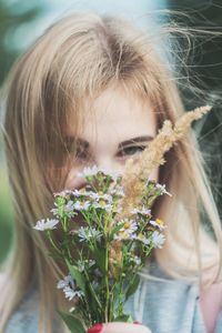 Close-up portrait of young woman holding white flowers