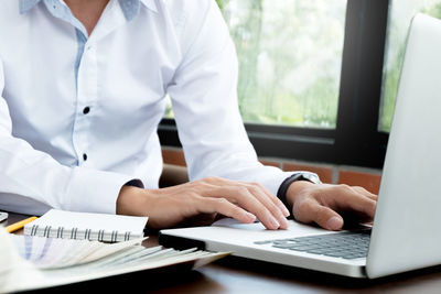 Midsection of man using laptop on table