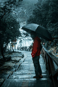 Full length of person standing on wet footpath during monsoon