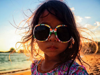 Portrait of girl wearing sunglasses at beach against sky