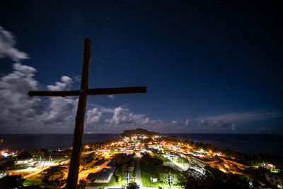 Cross against illuminated city at night
