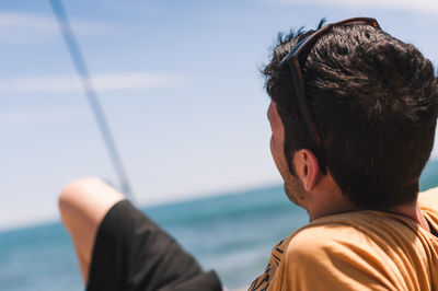 Rear view of man looking at sea against sky