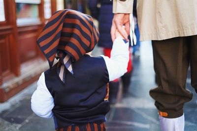 Rear view of father and son holding hands while walking on street