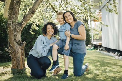 Portrait of smiling homosexual mothers with son in backyard