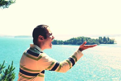 Optical illusion of man eating island against sky on sunny day