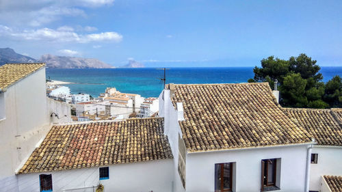 Mediterranean old town with blue sea, blue sky, palm tree, traditional rooftops, mountain landscape