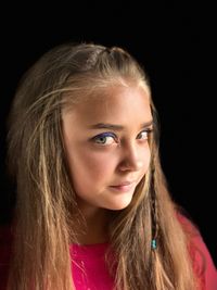 Close-up portrait of a beautiful young woman over black background