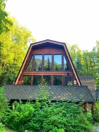 House amidst trees and building against clear sky