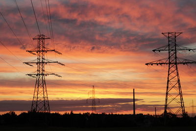 Low angle view of silhouette electricity pylon on field against romantic sky