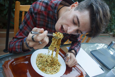 Close-up of man eating noodles at table