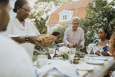 Male and female family members having lunch during family gathering at garden party