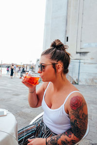 Young woman having drink while sitting outdoors