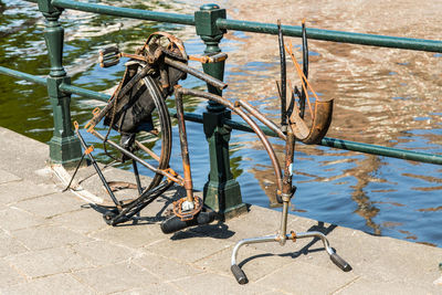 Abandoned bicycle parked by railing over lake