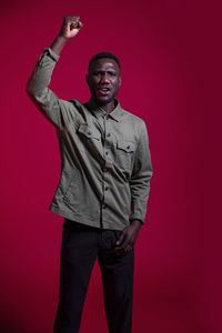 Portrait of young man standing against red background