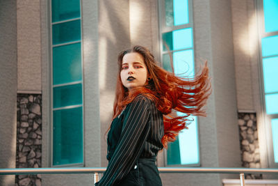 Portrait of woman standing against building