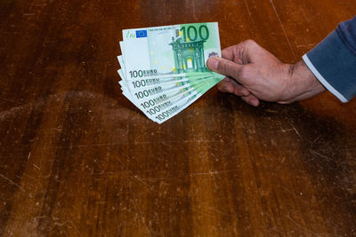 Close-up of hand holding paper with text on table