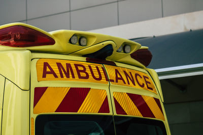 Close-up of yellow sign on car against wall