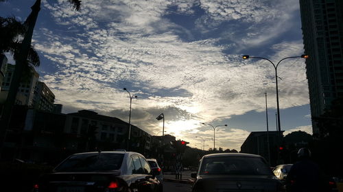 Traffic on city street against cloudy sky