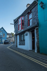 Road by buildings against blue sky