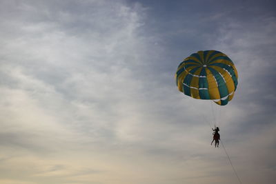 Low angle view of person paragliding against sky