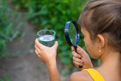 Girl looking at water through magnifying glass
