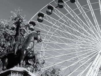 Low angle view of statue by ferris wheel against sky