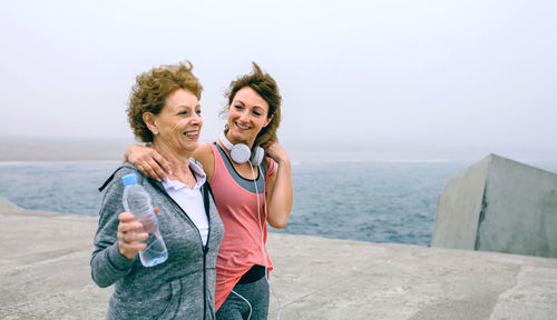 Woman with mother walking on pier against sky