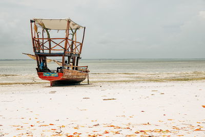 Boat at beach against sky during sunny day