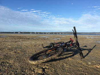 Bicycle on beach against sky