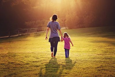 Full length rear view of siblings walking on landscape