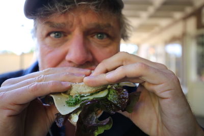 Close-up portrait of man eating sandwich