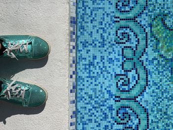 Low section of person standing by swimming pool