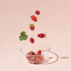 Close-up of red berries on table against white background