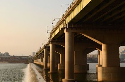 Bridge over river in city against clear sky