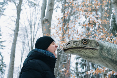 Side view of man looking at dinosaur at forest