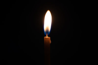 Close-up of lit candle in darkroom